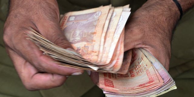 A man counts currency notes in Mumbai on June 20, 2013. Indian companies will be "severely" hit by the rupee's plunge to record lows due to their hefty foreign debts, the country's top credit ratings agency Crisil Research warned Wednesday.