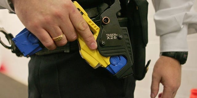 A police officer holds a Taser gun during a training session in Gravesend, Kent on December 5, 2007. A 23-year-old man has died after police shot him with a Taser stun gun, Greater Manchester police said on Thursday.