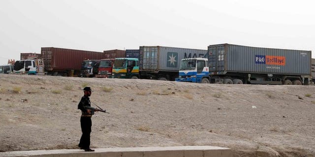 A Pakistani security serviceman stands guard beside container trucks parked at the border town of Chaman on July 27, 2012. A bomb explosion on Thursday killed at least two people and wounded eight others including four paramilitary Frontier Corps (FC) officials in a southwestern Pakistani town near the Afghan border, officials said.