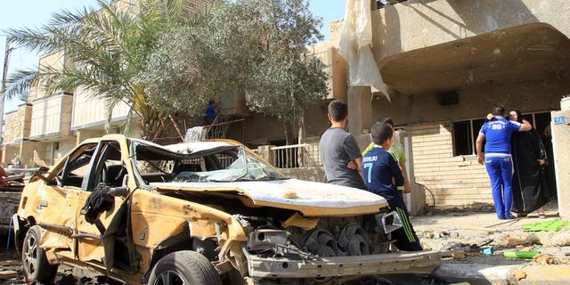 Iraqis sit on a damaged car after a car bomb explosion near a Shiite Islamic center in the Baghdad neighbourhood of Qahira on March 29, 2013. A car bomb followed by a suicide bombing targeting people mourning a Shiite man killed 10 people and wounded 22 in Iraq on Thursday, police and a doctor said.