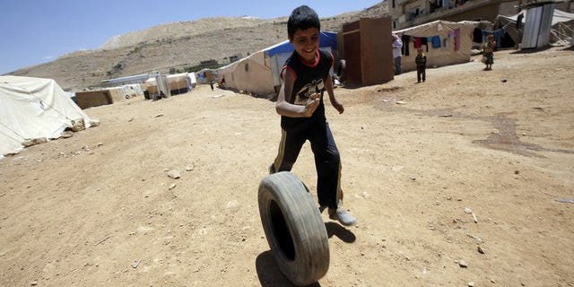 A young Syrian boy, who fled with his family after recent violence in Qusayr, plays with a tyre at the Arsal refugee camp on June 14, 2013 in Lebanon. A majority of Lebanese believe the influx of Syrian refugees in their country threatens national security, Norway's Fafo research foundation said in a report obtained on Thursday by AFP.