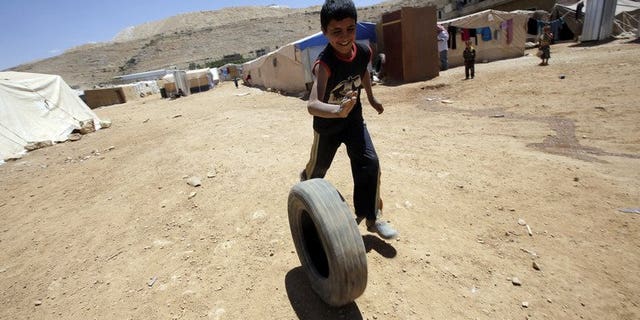 A young Syrian boy, who fled with his family after recent violence in Qusayr, plays with a tyre at the Arsal refugee camp on June 14, 2013 in Lebanon. A majority of Lebanese believe the influx of Syrian refugees in their country threatens national security, Norway's Fafo research foundation said in a report obtained on Thursday by AFP.