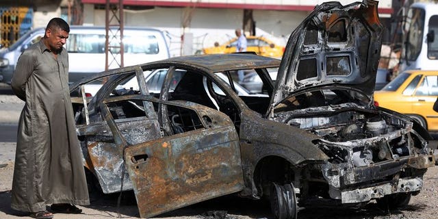 An Iraqi man inspects a burnt-out vehicle after a car bomb explosion in the Hurriyah area of Baghdad, on July 3, 2013. The toll from a wave of attacks in Iraq mainly targeting security forces and Shiites has risen to 51 killed, 26 of them police and soldiers, security officials and doctors said.