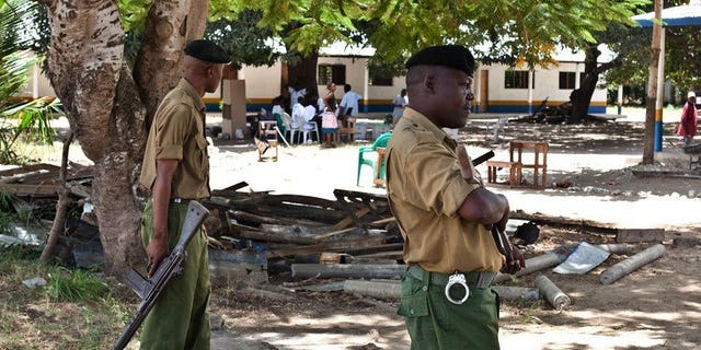 File picture shows police officers on guard at a polling station in Kakuyuni in the coastal Kenyan town of Malindi on February 24, 2013. Three foreigners facing terrorism charges at home have been charged with illegally entering Kenya and are set to be deported, lawyers and officials said Friday.