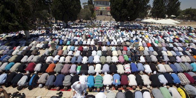 Palestinian worshipers pray outside the Dome of the Rock at the Al-Aqsa Mosque compound in Jerusalem during the first Friday prayers of the Muslim holy fasting month of Ramadan on July 12, 2013.