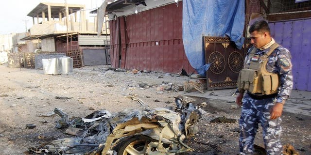 An Iraqi soldier inspects the wreck of a car bomb in the northern Iraqi city of Kirkuk on July 11, 2013. A suicide bomber targeting a cafe in the town killed at least 18 people and wounded 28, police and medical sources said.