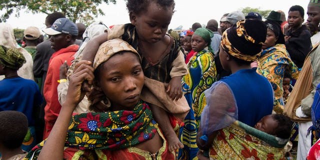 A mother carries her baby at Rwamwanja refugee camp in western Uganda on February 28, 2013. More than 30,000 refugees from eastern Democratic Republic of Congo fleeing a rebel attack on the town of Kamango have arrived in neighbouring Uganda, UN officials have said.