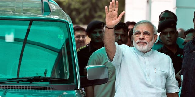 Bharatiya Janata Party (BJP) leader Narendra Modi waves on his arrival at party headquarters in New Delhi, on July 8, 2013. Modi -- seen as the key opposition challenger in 2014 elections -- has said he meant no offence when he compared victims of anti-Muslim violence to puppies run over by a car.