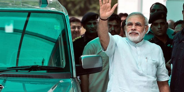 Bharatiya Janata Party (BJP) leader Narendra Modi waves on his arrival at party headquarters in New Delhi, on July 8, 2013. Modi -- seen as the key opposition challenger in 2014 elections -- has said he meant no offence when he compared victims of anti-Muslim violence to puppies run over by a car.