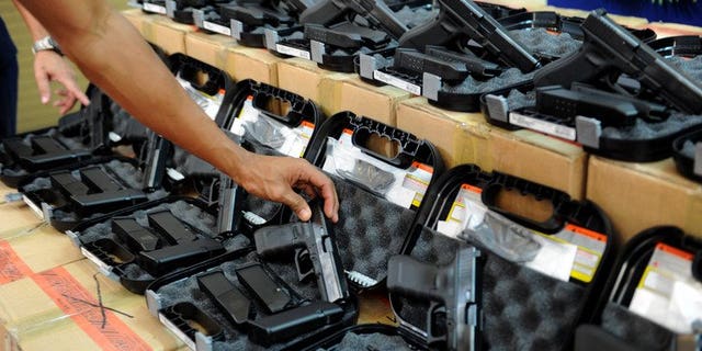 A Philippine police officer inspects pistols during a ceremony in Manila, on July 2, 2013. The Philippines is to investigate a group of police officers who were allegedly filmed executing a criminal, the government's human rights commission said Saturday.