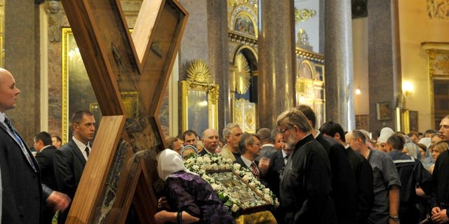 An Orthodox worshipper kisses the cross of Saint Andrew durng a ceremony at Kazan Cathedral in Saint Petersburg, on July 11, 2013. Around 65,000 people have queued for hours in Saint Petersburg to see a religious relic brought from Greece, in the latest sign of the Russian Orthodox Church's influence in post-Soviet Russia.