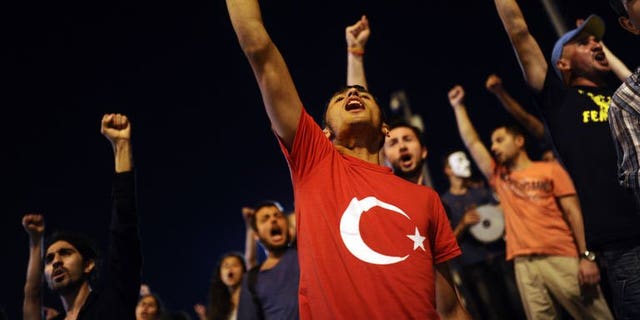 Turkish anti-government protesters shout slogans at the entrance of Gezi Park on July 11, 2013 in Istanbul. Turkish riot police on Saturday fired rubber bullets, tear gas and water cannon to disperse hundreds of protesters trying to enter an Istanbul square that was the cradle of deadly unrest that engulfed the country in June.