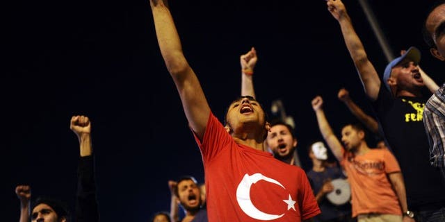 Turkish anti-government protesters shout slogans at the entrance of Gezi Park on July 11, 2013 in Istanbul. Turkish riot police on Saturday fired rubber bullets, tear gas and water cannon to disperse hundreds of protesters trying to enter an Istanbul square that was the cradle of deadly unrest that engulfed the country in June.