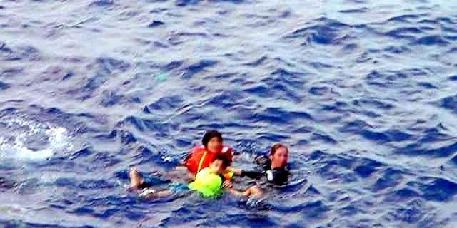 In this file photo, an Australian Navy officer (R) rescues two refugee children from the sea off Christmas Island, on October 10, 2001. The rescue authorities on Sunday said a search for eight people missing after a boat carrying 97 asylum-seekers sank in remote seas had ended, with little chance anyone would be found alive.