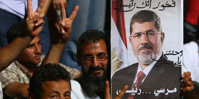 Supporters of deposed Egyptian president Mohamed Morsi flash the victory sign during a rally outside Cairo's Rabaa al-Adawiya mosque on June 10, 2013.