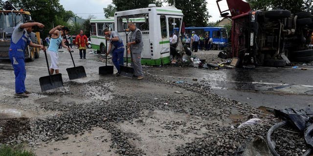 Men clear the crash scene near the village of Oznobikhino, on July 13, 2013. Russian investigators have interrogated the hospitalised driver of a truck that ploughed into a packed passenger bus outside Moscow killing 18 people.