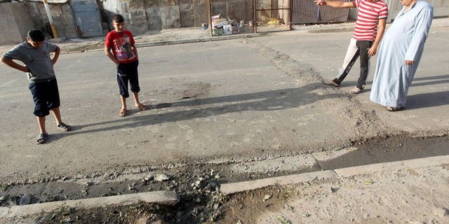 Iraqi's inspect a crater after an explosion the day before in the Dura area of south Baghdad, on July 14, 2013. Violence in Iraq -- including attacks on two members of a district council in the north -- has killed eight people, officers and doctors tell AFP.