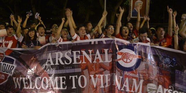 Vietnamese football fans cheer as they wait for the arrival of Arsenal players at Hanoi airport on July 15, 2013. Hundreds of cheering Vietnamese football fans turned out to greet Arsenal as they became the first English Premier League club to visit the football-mad communist country.