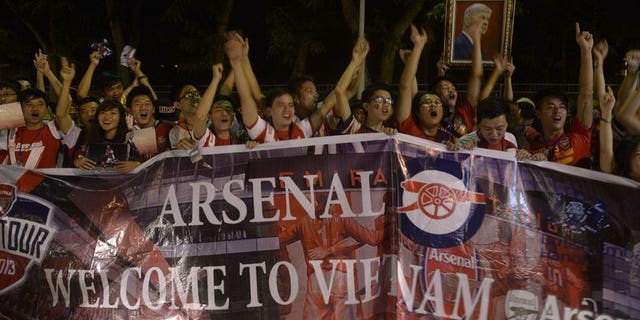 Vietnamese football fans cheer as they wait for the arrival of Arsenal players at Hanoi airport on July 15, 2013. Hundreds of cheering Vietnamese football fans turned out to greet Arsenal as they became the first English Premier League club to visit the football-mad communist country.