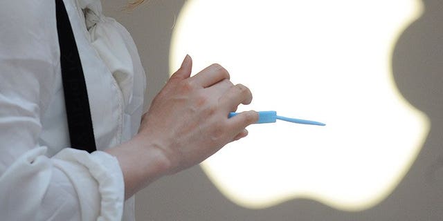 A woman uses her mobile phone outside an Apple store in Shanghai, on May 7, 2012. Apple has said it will investigate claims that an iPhone electrocuted a Chinese woman who was making a call while charging the device.