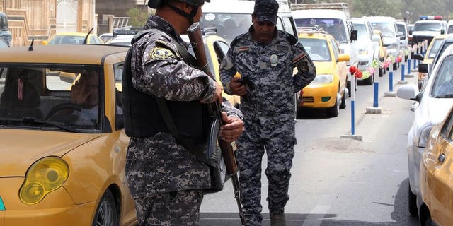 Iraqi security officers keep watch at a checkpoint in Baghdad on May 29, 2013. Four people were killed and nine wounded when a group of people were struck by mortars as they gathered for a swim on a bank of the Tigris river north of Baghdad