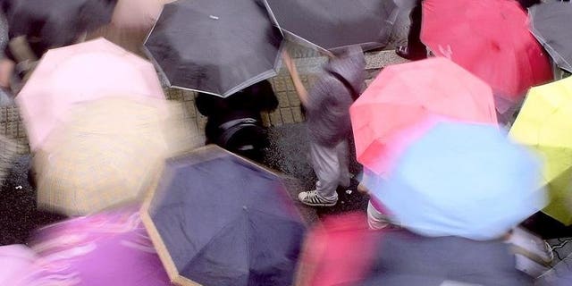 South Koreans carry colorful umbrellars as they cross a street in Seoul, on May 28, 2004. Three South Koreans have been confirmed dead or missing after heavy rains pounded the Korean peninsula, leaving hundreds homeless as the downpours left a trail of destruction in the two Koreas.