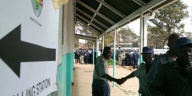 Police officers queue outside a polling station to vote during the special voting day for registered members of the police and army in Harare on July 14, 2013. Local election monitors called Monday for Zimbabwe to extend early voting for thousands of police officers and warned the country's electoral system was in disarray two weeks from a crucial presidential poll.