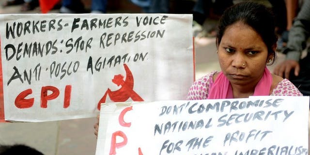A woman holds an anti-US, South Korean and Indian government placard during a protest in New Delhi on April 12, 2013 against farmland being converted into an industrial development area by South Korean steel giant Posco. Posco said Tuesday it would scrap a $5.3 billion deal to build a steel plant in India because of delays and local opposition.