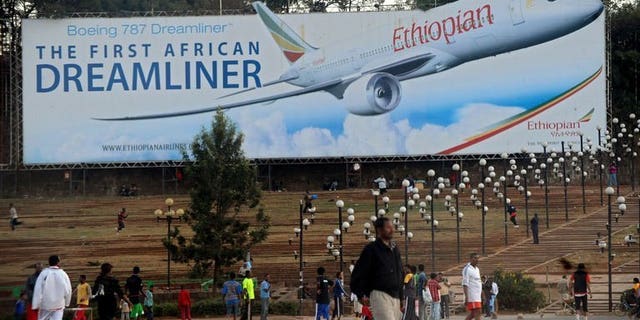 Picture dated January 27, 2010 shows people walking past a billboard in Addis Ababa showing an Ethiopian Airlines Boeing 787 Dreamliner plane. British investigators said Tuesday they were examining a transmitter made by US group Honeywell as part of a probe into a fire on an Ethiopian Airlines Dreamliner jet at London's Heathrow Airport.