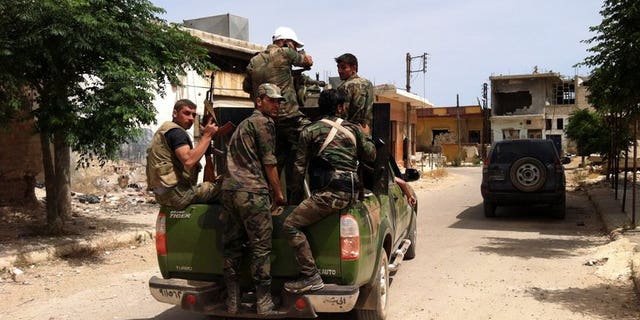 Syrian army soldiers patrol a street in the village of Buweida, north of Qusayr, in Syria's central Homs province, on June 8, 2013. Members of a Syrian pro-regime militia gunned down seven Sunni men working on reconciliation in the central province of Homs overnight, the Syrian Observatory for Human Rights said on Tuesday.