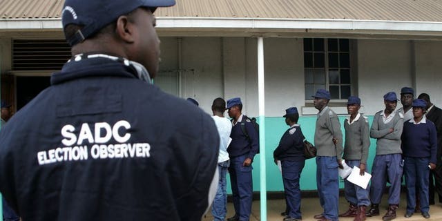 An election observer looks on as Zimbabwe security forces queue to vote in Harare on July 14, 2013. Zimbabwean security personnel unable to cast their ballots during chaotic early polling this week will get another chance to vote on July 31, the country's elections chief has announced.