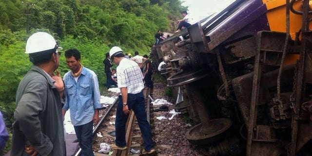 Rescue workers at the site of a Bangkok-Chiang Mai express service train that derailed from its tracks in Phrae province, northern Thailand on July 17, 2013. Foreign tourists were among 23 people injured when the overnight sleeper train derailed early Wednesday, the national rail operator said.