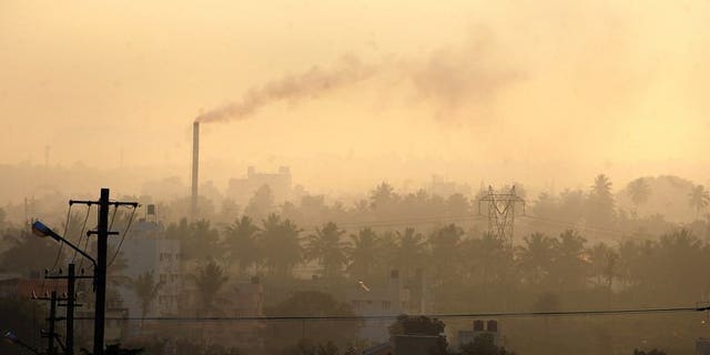 A factory chimney belches smoke in a residential area as haze casts a blanket over Bangalore, southern India on December 11, 2009. Pollution and other environmental degradation costs India $80 billion a year, nearly six percent of gross domestic product, the World Bank said in a report released on Wednesday.