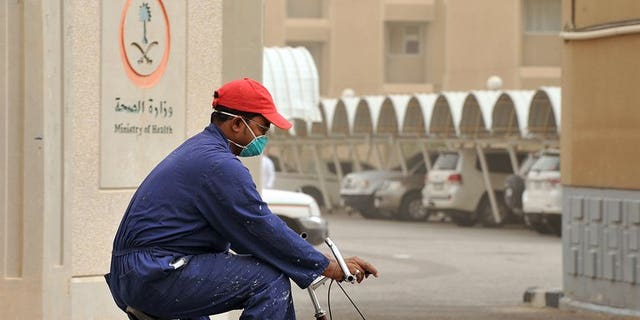 A man wears a mask as he rides a bicycle near the King Fahad hospital in the city of Hofuf, Saudi Arabia on June 16, 2013. The World Health Organization on Wednesday held off from calling for travel restrictions related to the MERS virus striking hardest in Saudi Arabia, after emergency talks on the mystery illness.