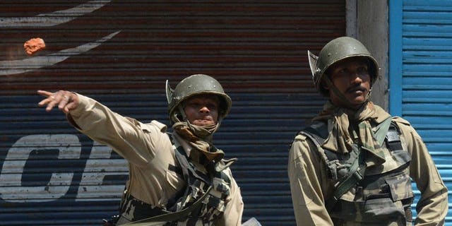 An Indian paramilitary trooper throws a brick towards Kashmiri protesters on on July 18, 2013 during a protest over the killing of six villagers in Srinagar. Indian paramilitary troops Thursday shot dead six people protesting outside a Border Security Force station in Kashmir, two police officers said.