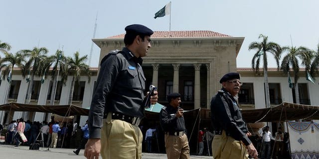 Pakistani police officers walk past Punjab provincial assembly building in Lahore on June 1, 2013. Police in Pakistan have arrested a cook on suspicion of murder after 22 members of a powerful landowning clan were poisoned in an alleged political feud with a rival branch of the family.