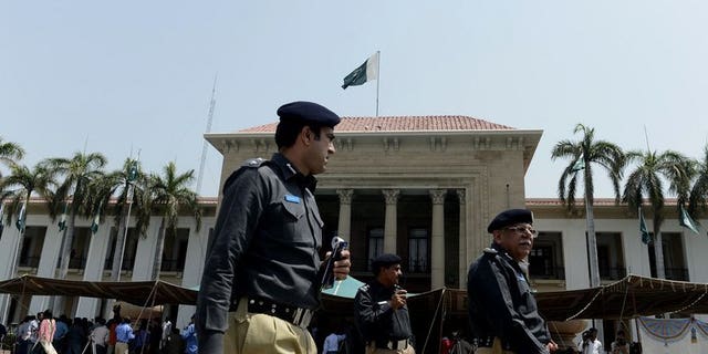 Pakistani police officers walk past Punjab provincial assembly building in Lahore on June 1, 2013. Police in Pakistan have arrested a cook on suspicion of murder after 22 members of a powerful landowning clan were poisoned in an alleged political feud with a rival branch of the family.