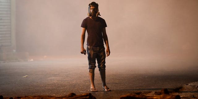 A Bahraini protester wearing a gas mask stands amid tear gas fired by riot police during clashes in the village of Diraz, west of Manama, in the early hours of July 19, 2013. Bahraini security forces clashed with anti-regime protesters early Friday, leaving several people wounded including a policeman who was shot with a home-made gun, the interior ministry and witnesses said.