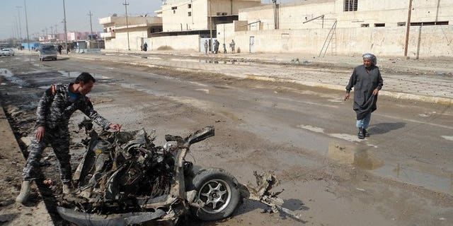 An Iraqi policeman inspects the debris of a vehicle following a blast in Baquba, capital of Diyala province, on February 23, 2012. A bomb exploded in a crowded mosque north of Baghdad on Friday afternoon, killing at least 20 people and wounding 40, police said.