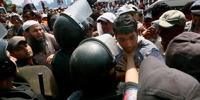 A supporter of Egypt's ousted president Mohamed Morsi is held back by riot police during a rally in Cairo on July 17, 2013. Britain has announced it is revoking export licences for equipment used by Egypt's military and police amid concerns it could be used against protesters.