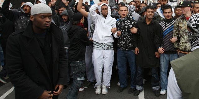 Michael Adebolajo (left) walks by a line of people near Harrow Mosque in London on September 11, 2009. Prison officers "strenuously deny any wrongdoing," their union said Friday, after Adebolajo lost two teeth when being restrained in jail.