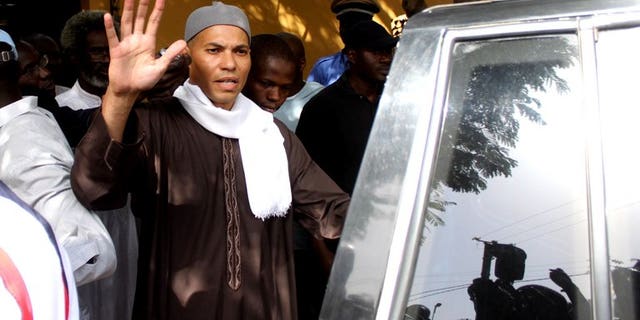 The son of former Senegalese leader Abdoulaye Wade, Karim, waves while being arrested on April 2013 in Dakar. A court ruled his rights were not violated.