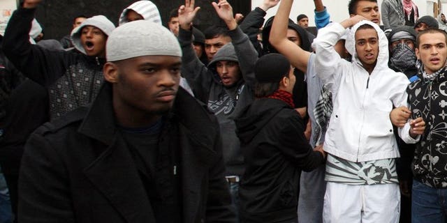 Michael Adebolajo (left) walks by a line of people near Harrow Mosque in London on September 11, 2009. Five staff at a London jail have been suspended after Adebolajo, one of the men accused of murdering a British soldier, reportedly lost two teeth while being restrained, officials said