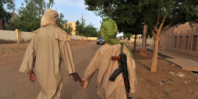 Two young fighters of an Islamist group walk in the streets of Gao city in Mali on July 17, 2012. Gunmen have abducted four polling staff and a local official in the northern Malian town of Tessalit, a week before a presidential poll meant to restore the country's unity, a local official said.