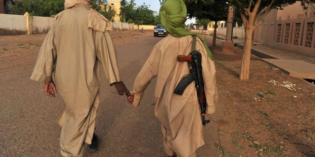 Two young fighters of an Islamist group walk in the streets of Gao city in Mali on July 17, 2012. Gunmen have abducted four polling staff and a local official in the northern Malian town of Tessalit, a week before a presidential poll meant to restore the country's unity, a local official said.