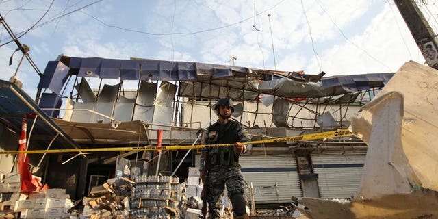 An Iraqi policeman inspects the damage outside a supermarket in central Baghdad's commercial Karrada neighbourhood on June 25, 2013. At least 22 people were killed in a string of car bomb attacks on Saturday timed for nightfall when shoppers take to the streets during Ramadan, security and medics said.