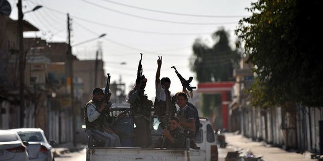 Syrian rebels raise their weapons during a patrol in the town of Tal Abyad near the border with Turkey on October 5, 2012. Syrian Kurdish fighters in the north fought fierce battles against jihadists and captured a commander of the Islamic State of Iraq and the Levant (ISIS) late Saturday, a monitoring group said.