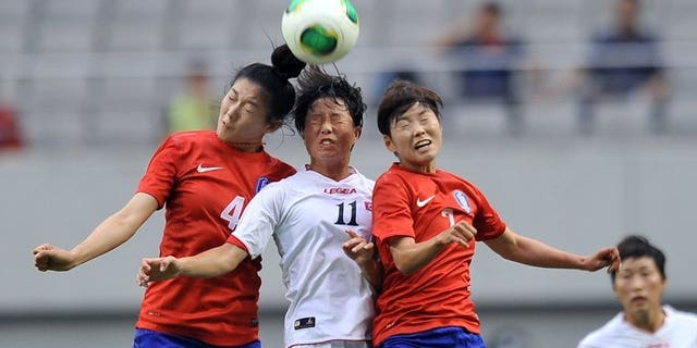 North Korea's Ri Ye-Gyong (centre) competes with South Korea's Shim Seo-Yeon (left) and Jeon Ga-Eul (right) during the Women's East Asian Cup football match in Seoul on July 21, 2013. North Korea won the match 2-1.