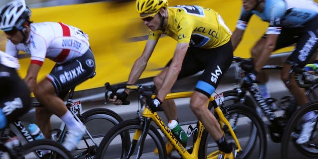 Overall leader's yellow jersey Britain's Chris Froome rides in the pack on the Champs Elysees avenue during the 133.5 km twenty-first and last stage of the 100th edition of the Tour de France cycling race on July 21, 2013 between Versailles and Paris. Froome was crowned the yellow jersey champion after winning the 100th Tour de France.