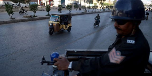 A Pakistani policeman stands guard on a police van in Karachi on February 8, 2013. A hand grenade attack targeting the office of a political party late Sunday killed at least two people and wounded six others in Pakistan's port city of Karachi, police said.